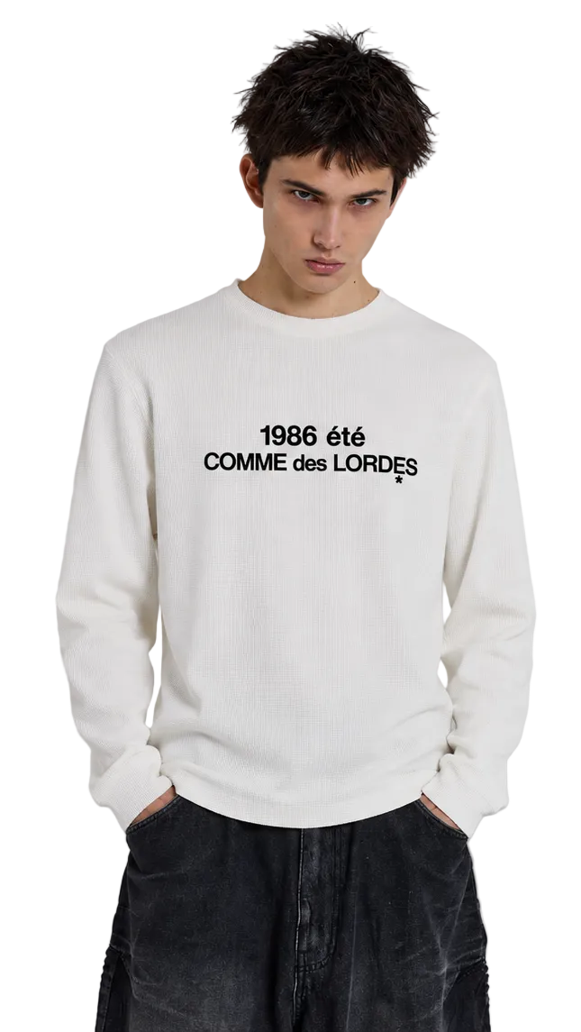 Front view of white COMME des LORDES long-sleeve top with black 1986 été lettering