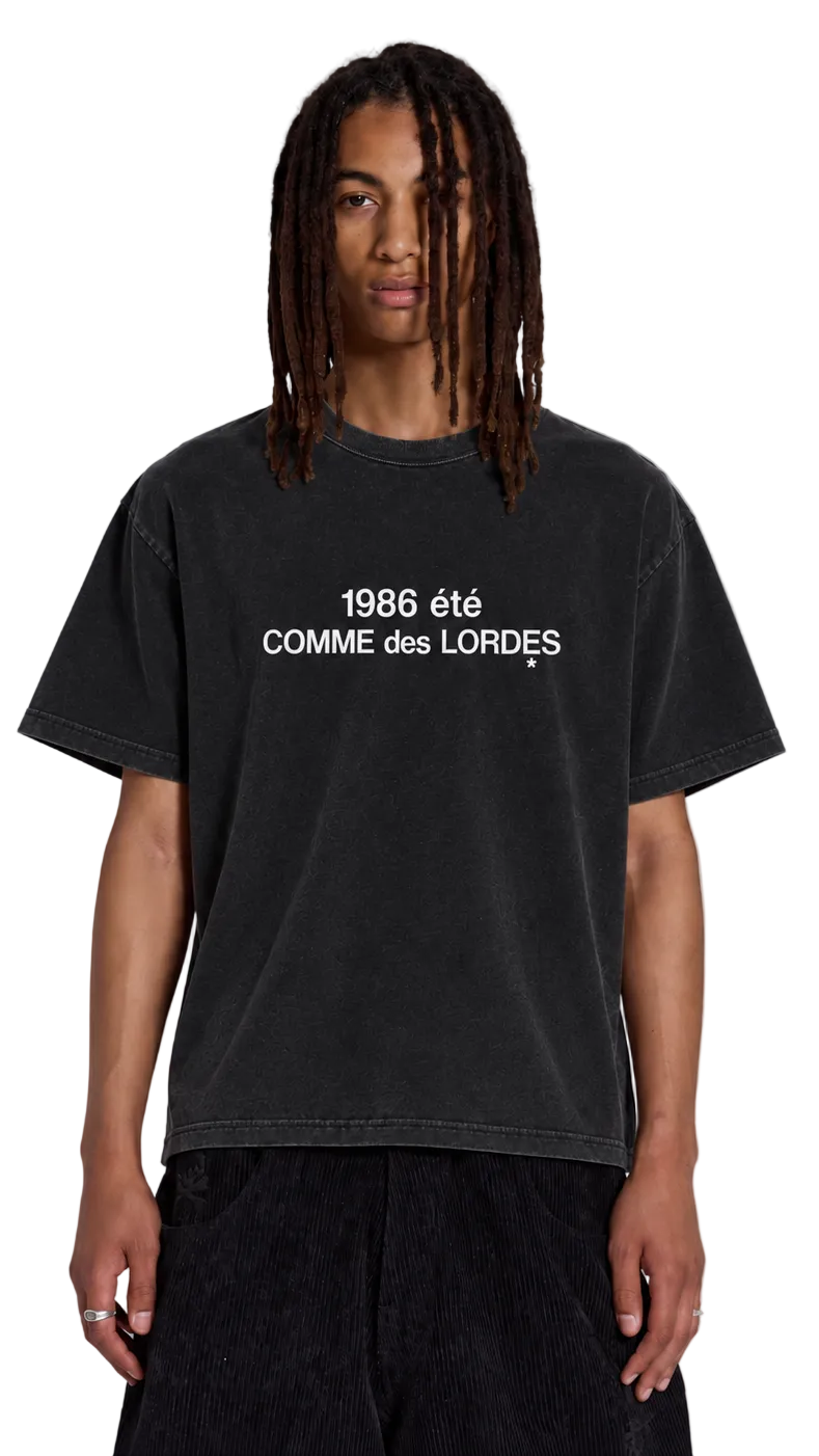 Front view of black COMME des LORDĘS tee with white 1986 été chest lettering