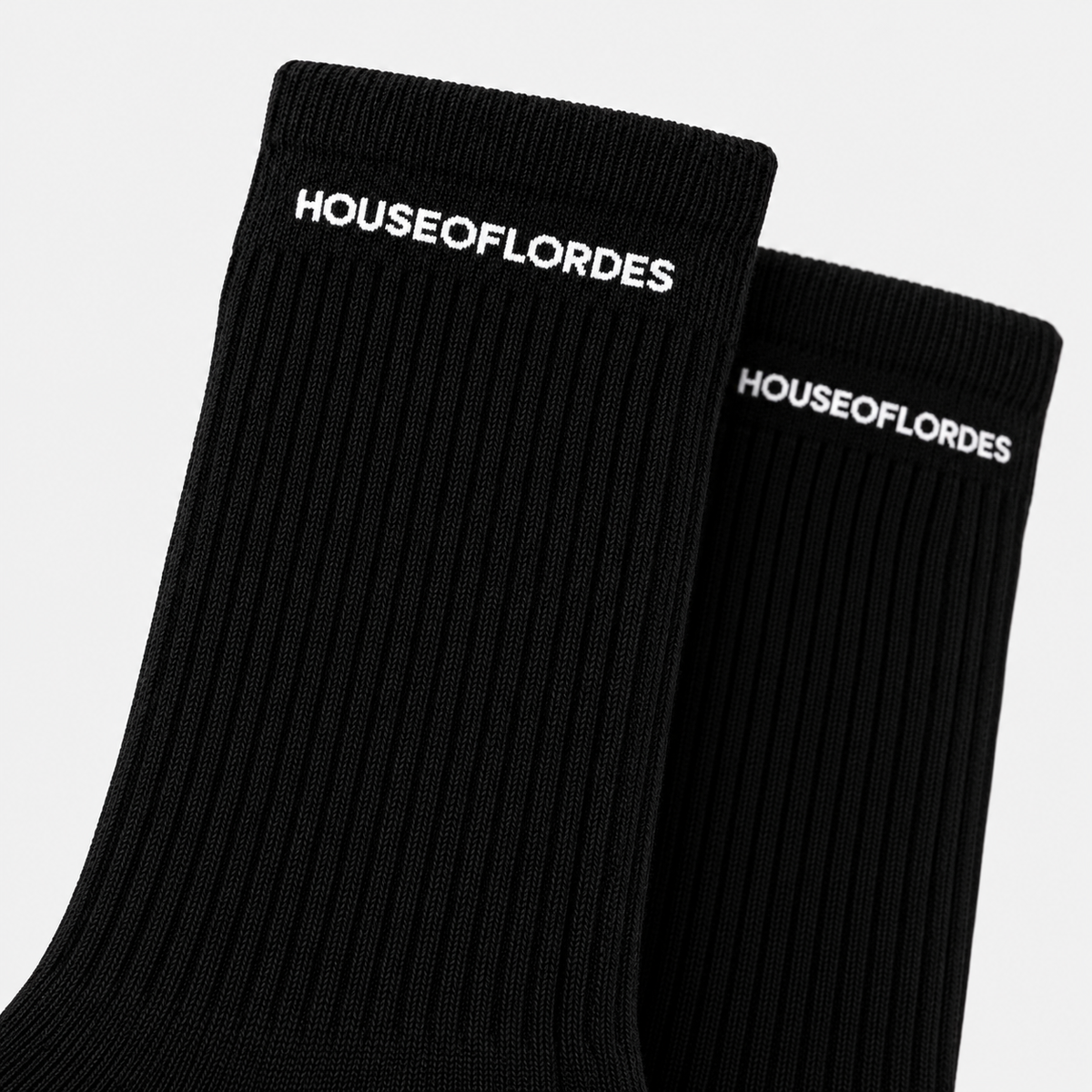 Close-up of white HOUSEOFLORDES lettering on black ribbed sock cuffs